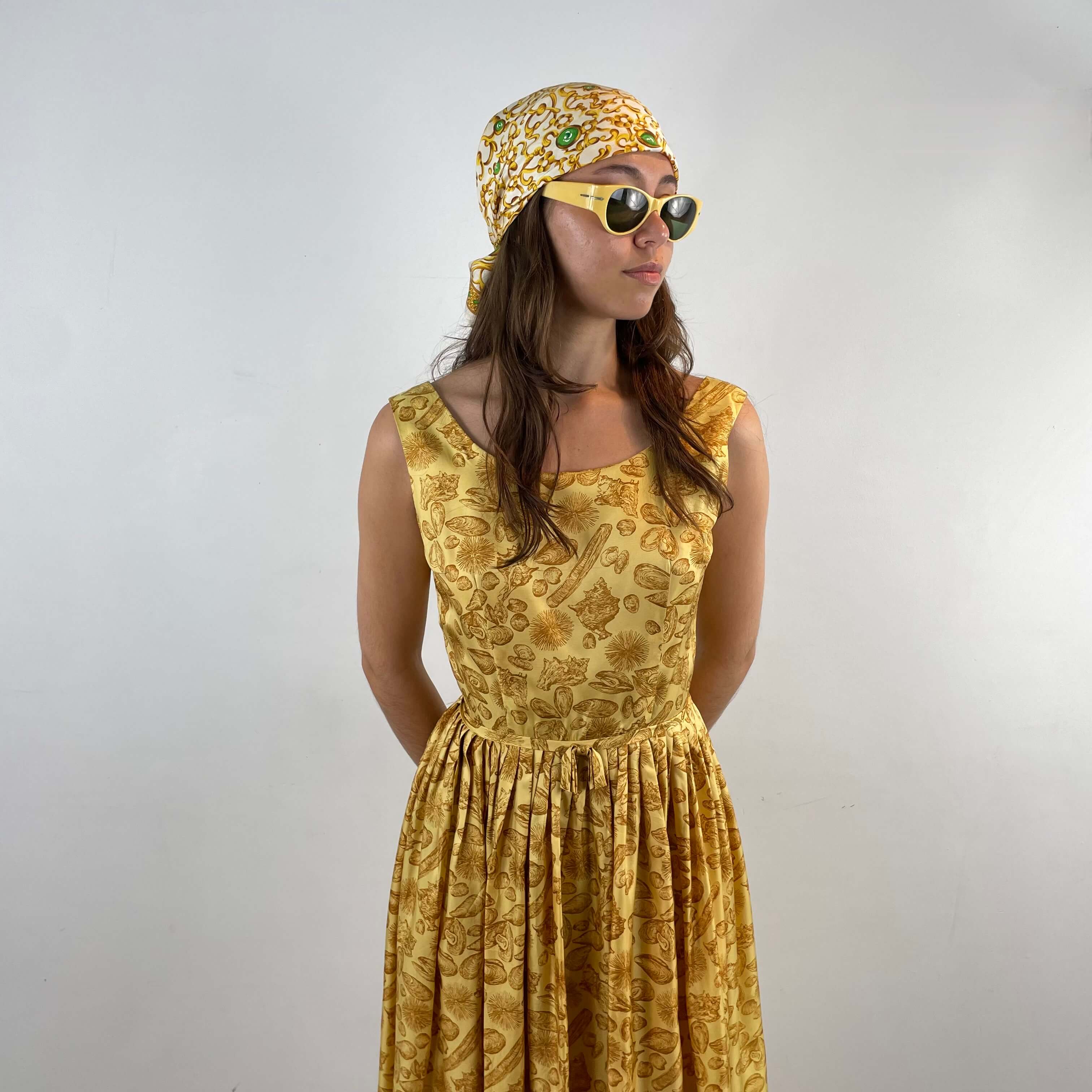 Front view of Boheme Vintage 1950s L’aiglon seashell print gold acetate dress with pleated skirt and fitted bodice.