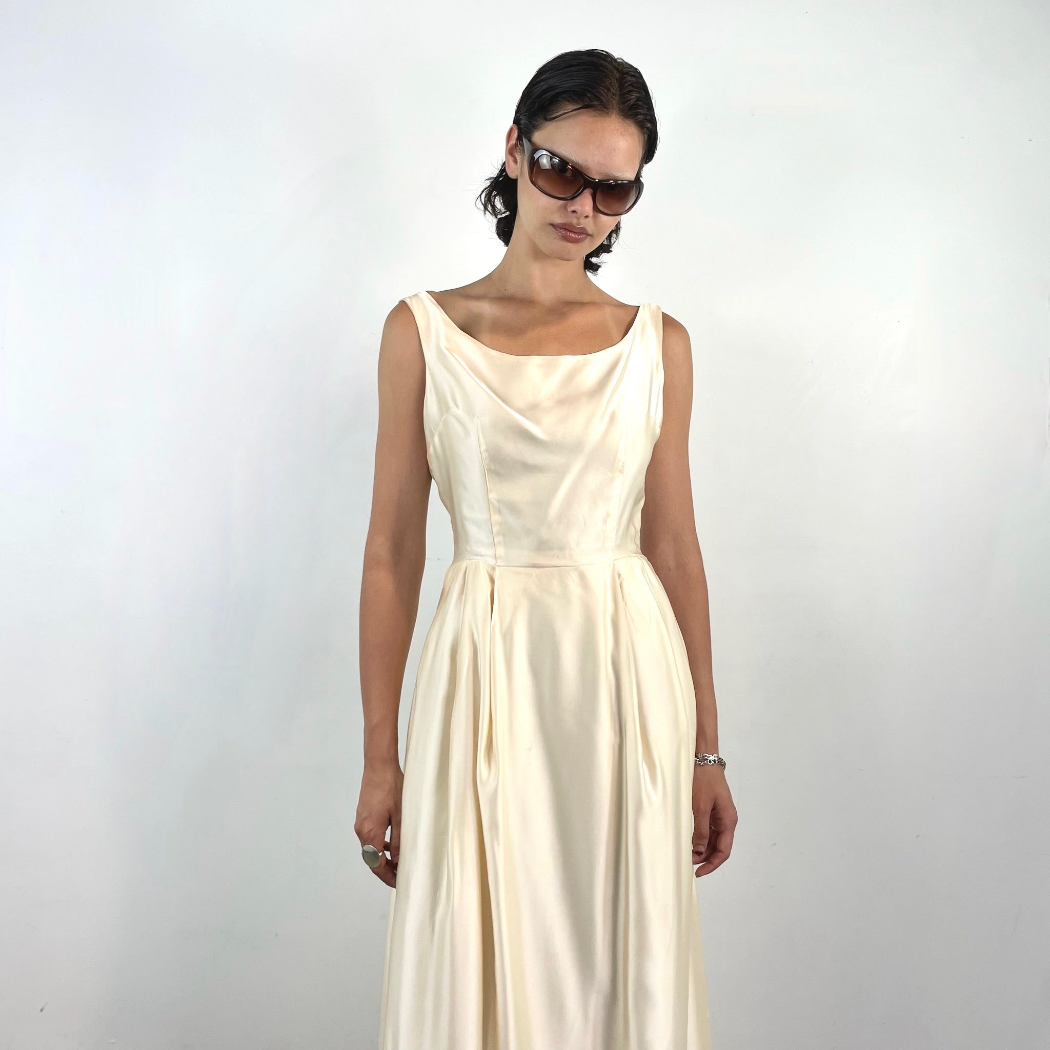 Boheme Vintage 1970s ivory satin gown with open back, pleated skirt, and fitted bodice.