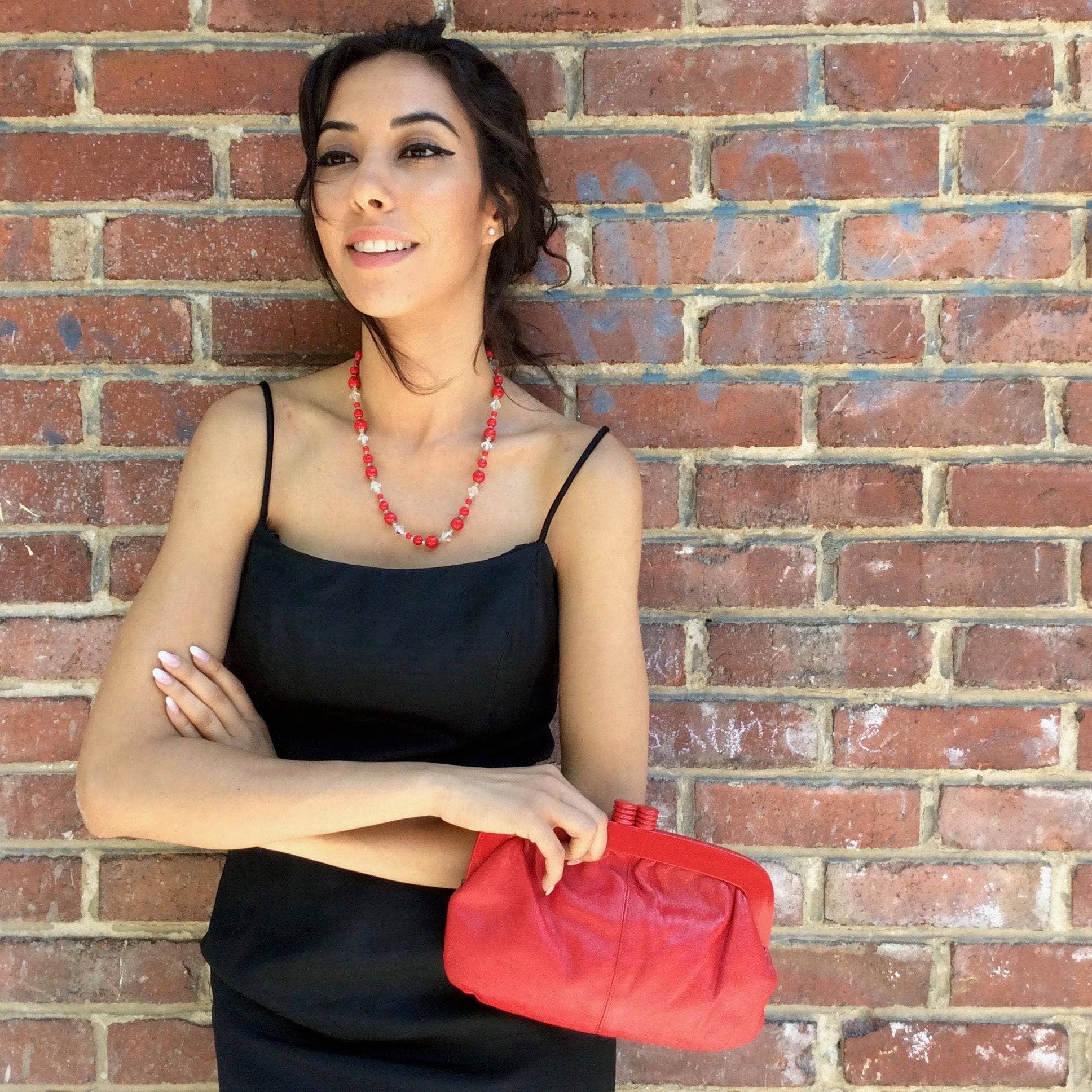 1950s Classic Black Silk Cocktail Dress Size Small Model is holding a 1980's Genuine Red Leather Clutch Handbag sold by bohemevintage.com Montreal