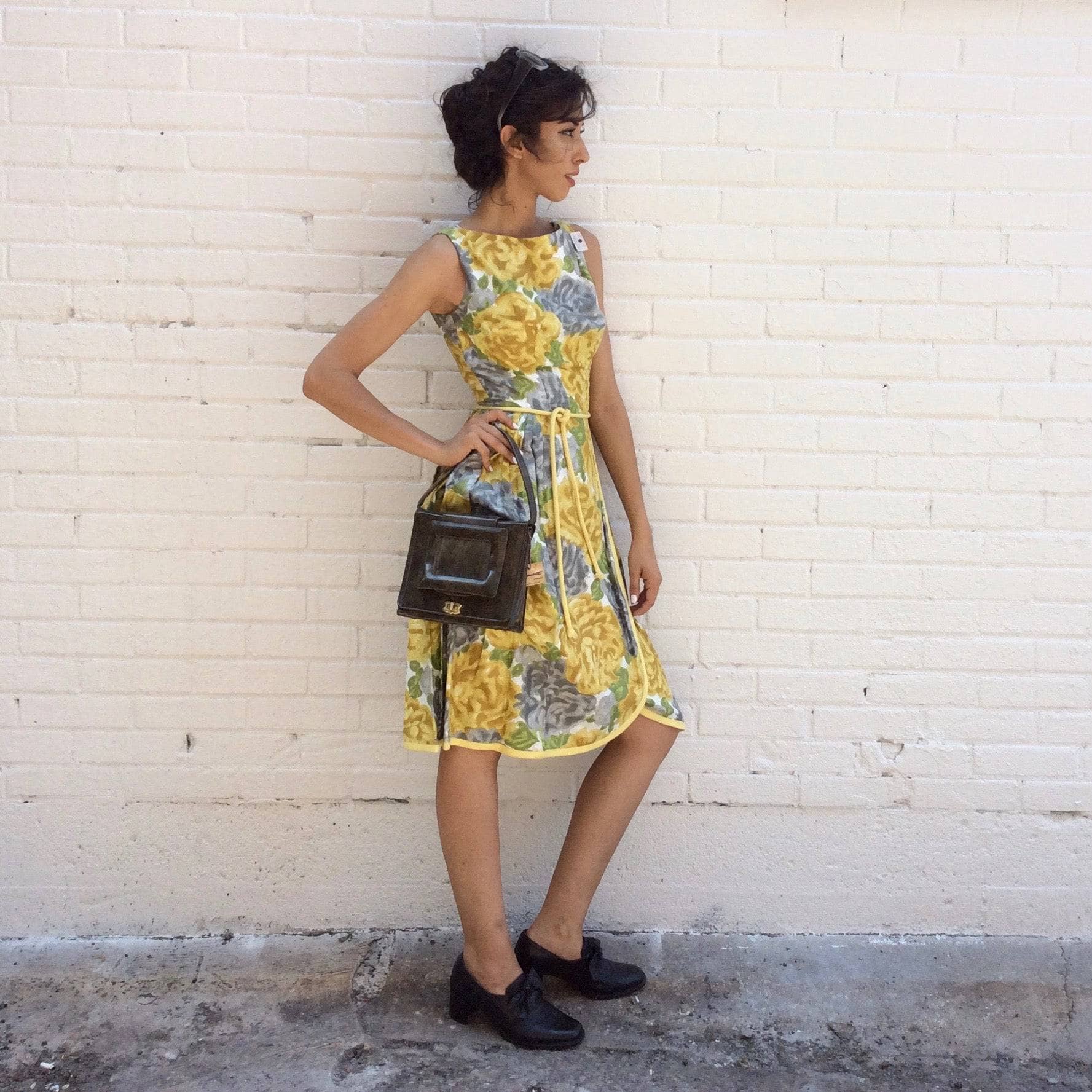 Side view of 1950s Yellow Floral Cotton Dress Size Small model is wearing 1960s Pillbox Handbag both sold by bohemevintage.com Montreal