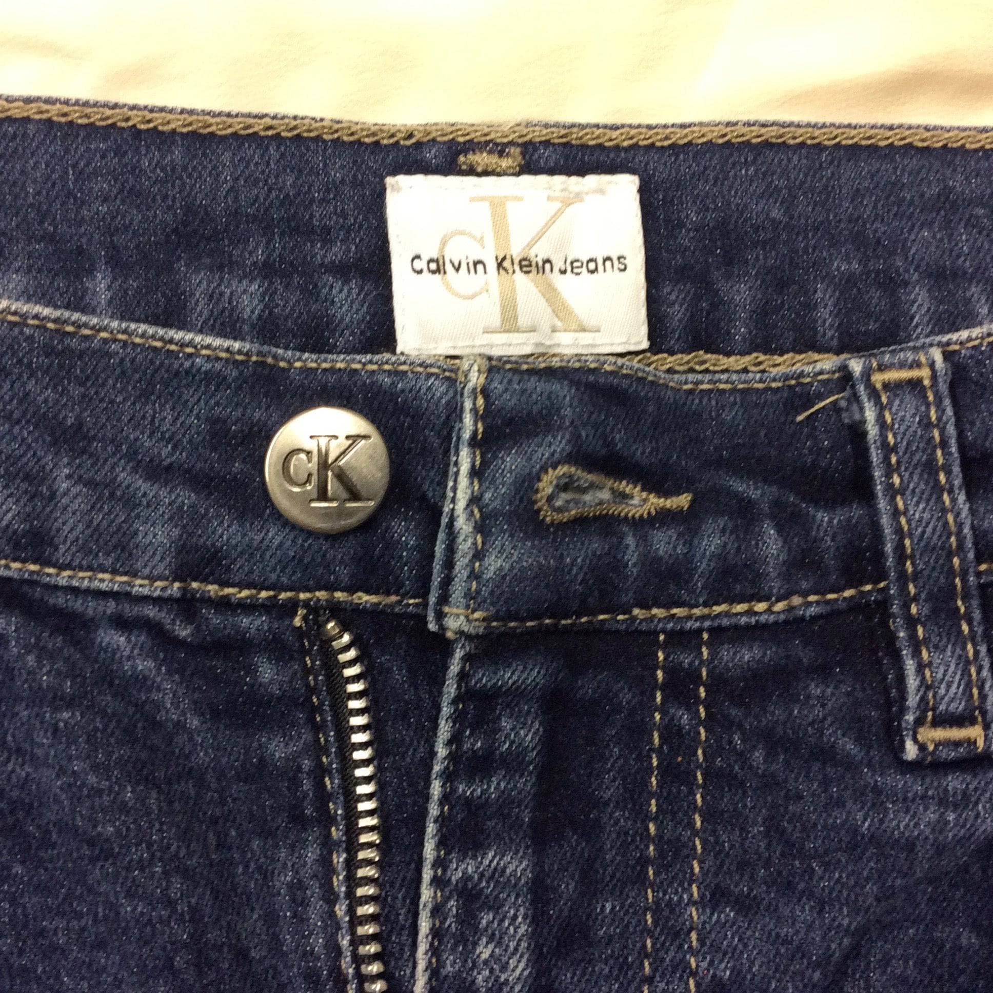Close-Up of waist button & Tag of 1990s Calvin Klein Medium Rise Denim Mini Skirt, Size Small, sold by bohemevintage.com Montreal