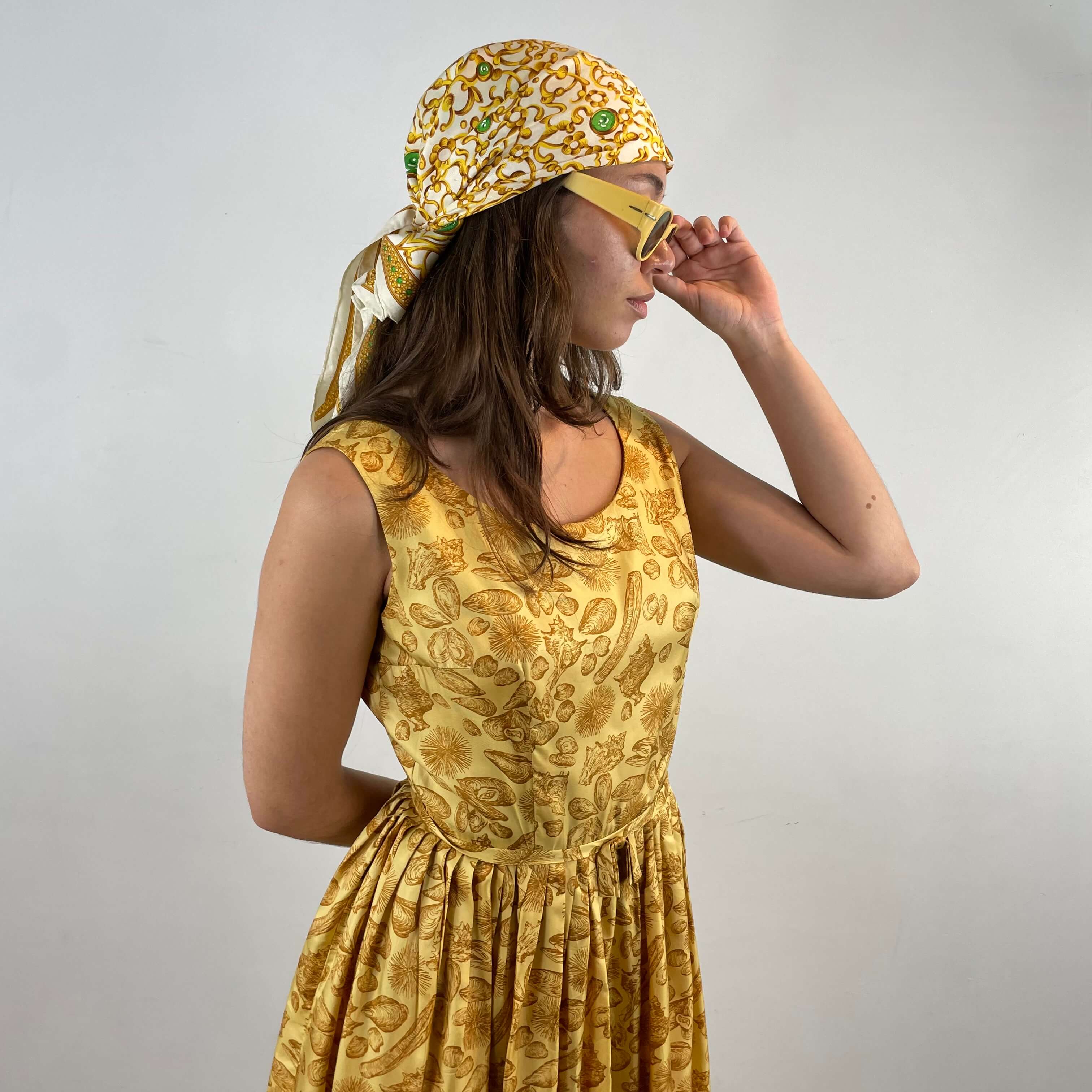 Side view of Boheme Vintage 1950s L’aiglon seashell print gold acetate dress with pleated skirt and fitted bodice.
