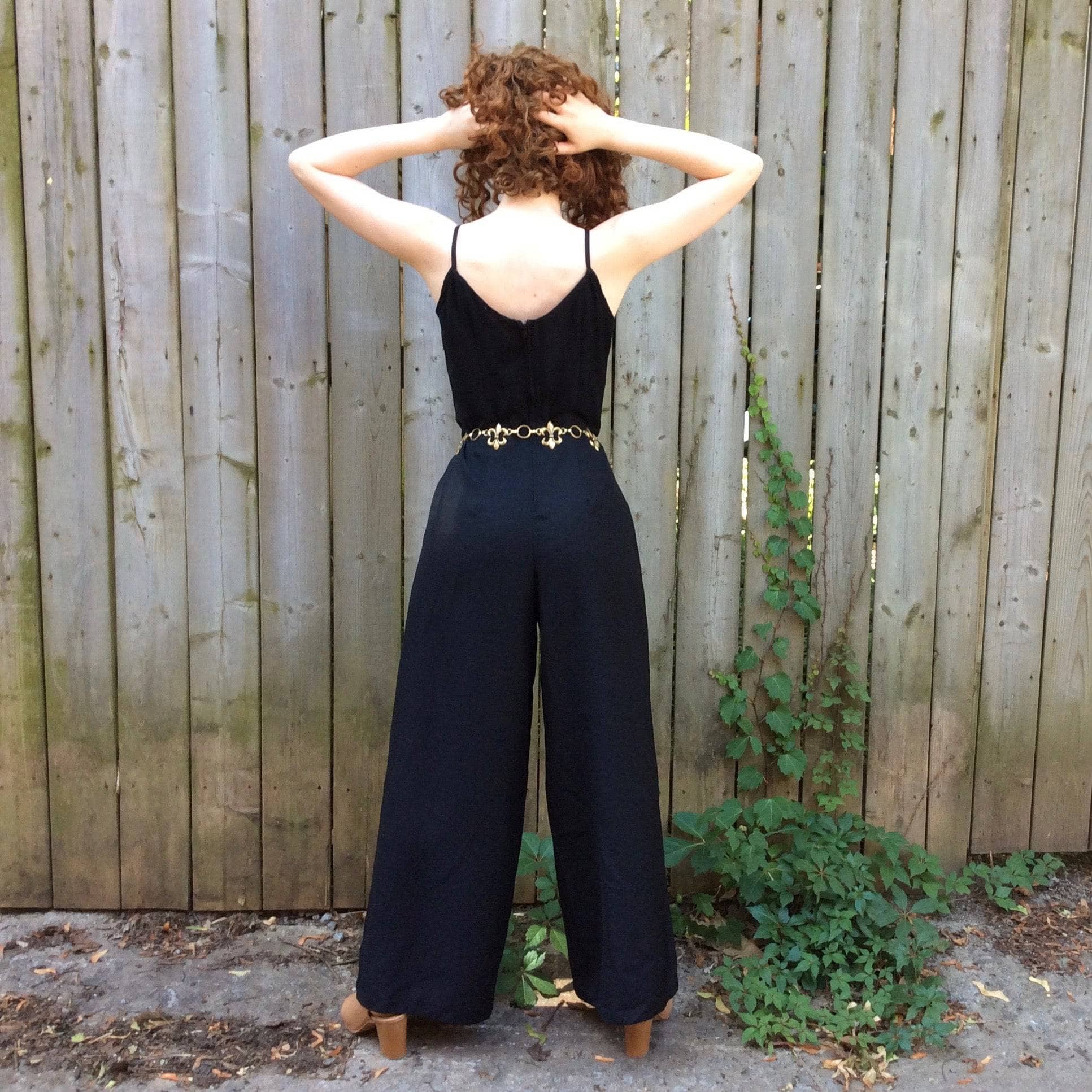 Back View of Boheme Vintage 1980s black wide-leg jumpsuit with fitted bodice, adjustable straps, and flowing silhouette.