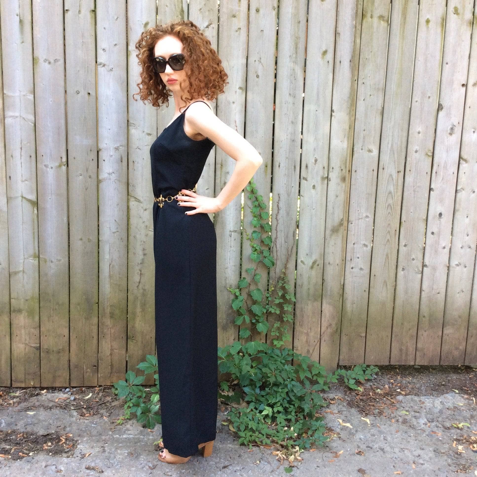 Side View of Boheme Vintage 1980s black wide-leg jumpsuit with fitted bodice, adjustable straps, and flowing silhouette.