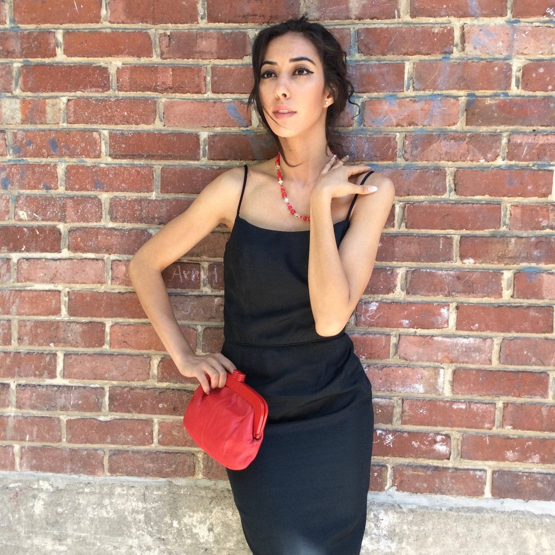 1950s Classic Black Silk Cocktail Dress Size Small Model is holding a 1980's Genuine Red Leather Clutch Handbag  sold  by bohemevintage.com Montreal 