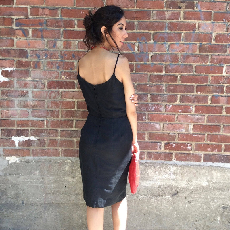 Backside View of 1950s Classic Black Silk Cocktail Dress Size Small Model is holding a 1980's Genuine Red Leather Clutch Handbag sold by bohemevintage.com Montreal 